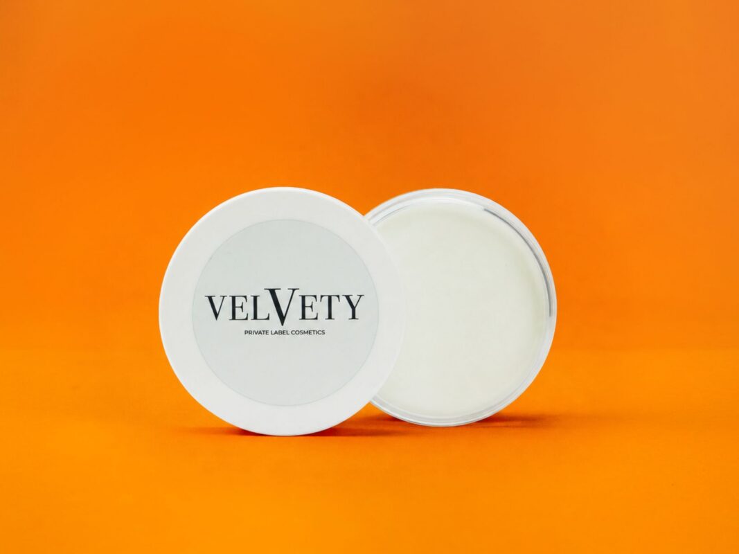 Geöffnete Velvety Kosmetikdose vor orangefarbenem Hintergrund.